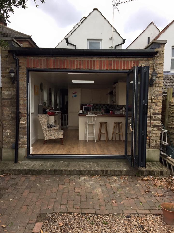 Anthracite aluminium bi-fold doors open onto a kitchen