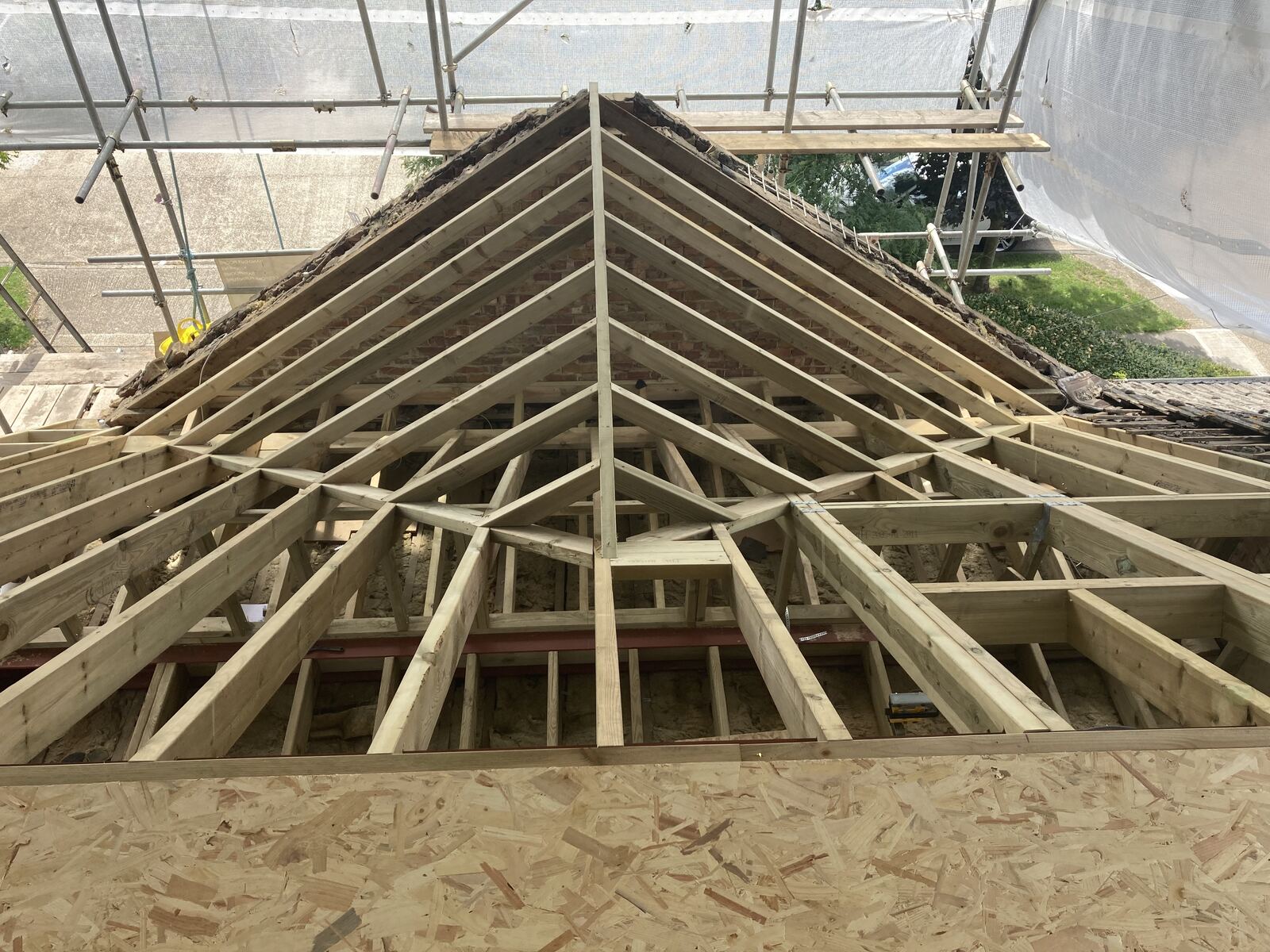 Roof carpentry mid-build, hip rafters exposed